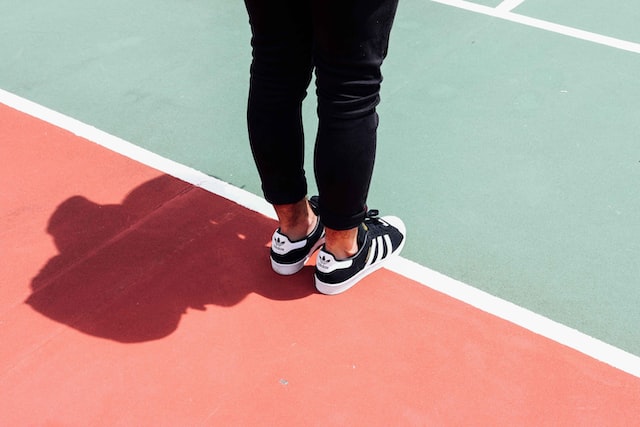 a man in sneakers stands on the edge of a sports field