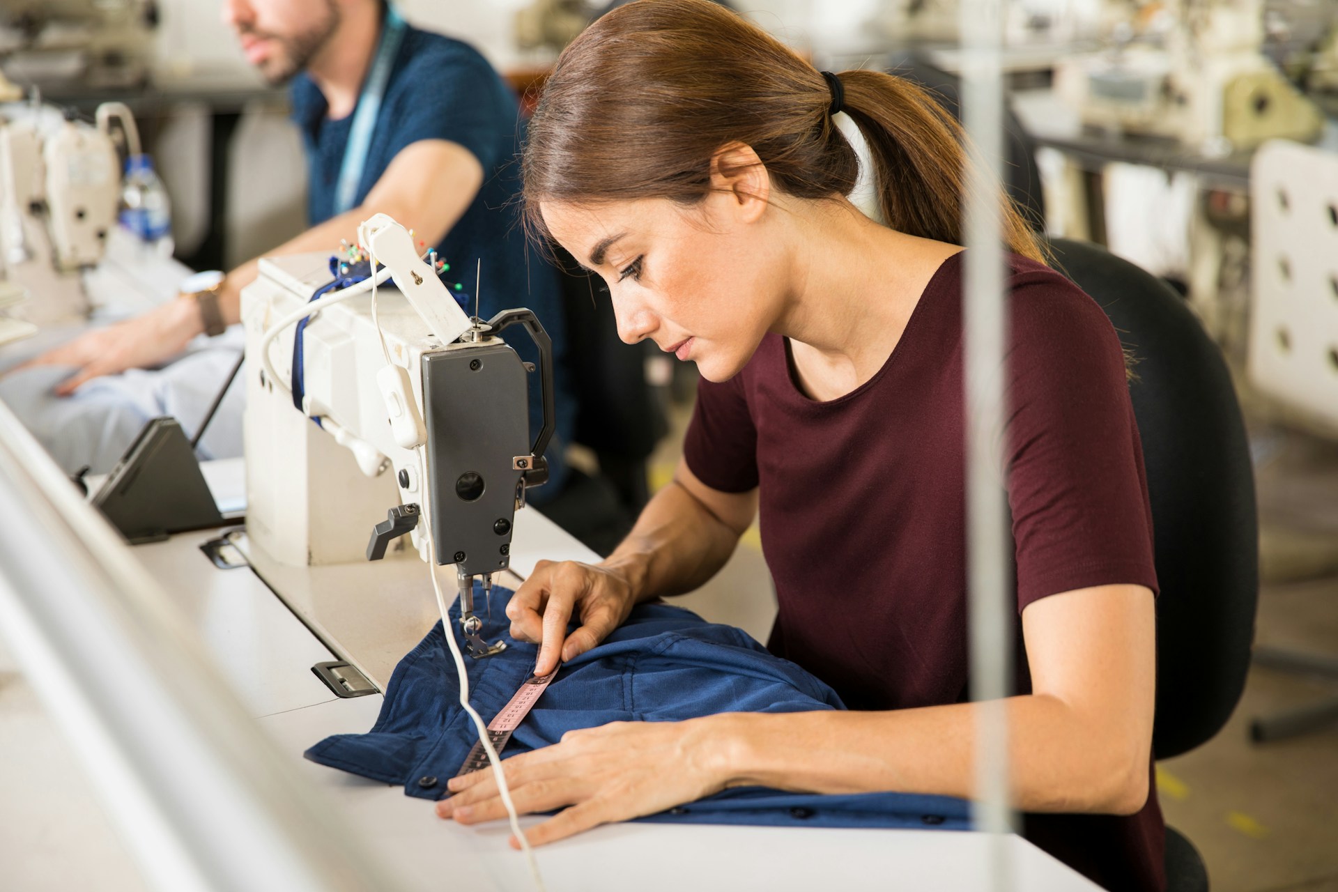 young-brunette-working-as-a-seamstress-and-measuring-a-shirt-after-doing-some-sewing-work