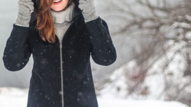 Winter Coat - A woman enjoying a snowy winter day, dressed warmly and smiling.