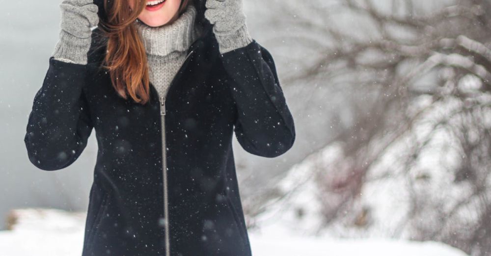 Winter Coat - A woman enjoying a snowy winter day, dressed warmly and smiling.