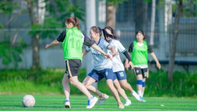 Budget-Friendly Shoes - Group of women engaged in a lively soccer match on a grassy field in Hanoi, Vietnam.