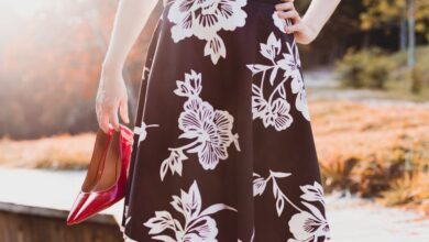 Skirts - Woman holding red heels, wearing a floral skirt, enjoying a sunny day outdoors.