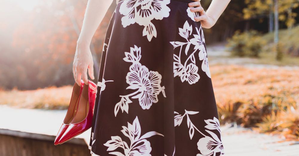 Skirts - Woman holding red heels, wearing a floral skirt, enjoying a sunny day outdoors.