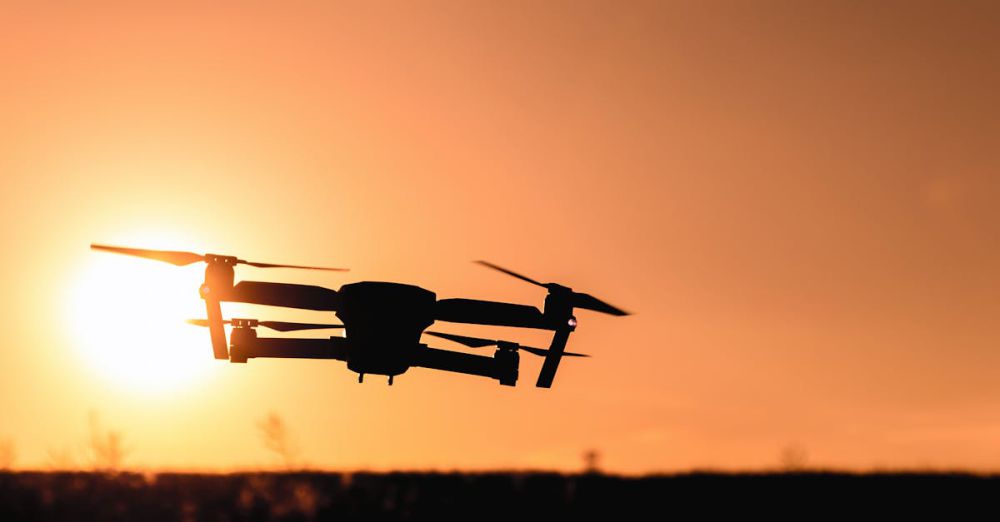 Drones - A drone in silhouette against a vibrant orange sunset sky, showcasing modern technology and aerial photography.