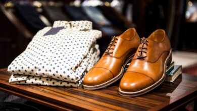 Men's Fashion - Elegant brown leather shoes and printed shirt displayed on a wooden table in a stylish clothing store.