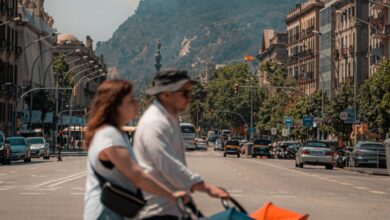 Baby Strollers - A family crossing a busy street in Barcelona with the cityscape and a stroller in view.