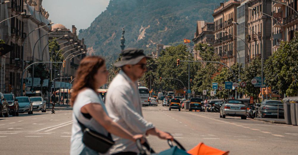 Baby Strollers - A family crossing a busy street in Barcelona with the cityscape and a stroller in view.