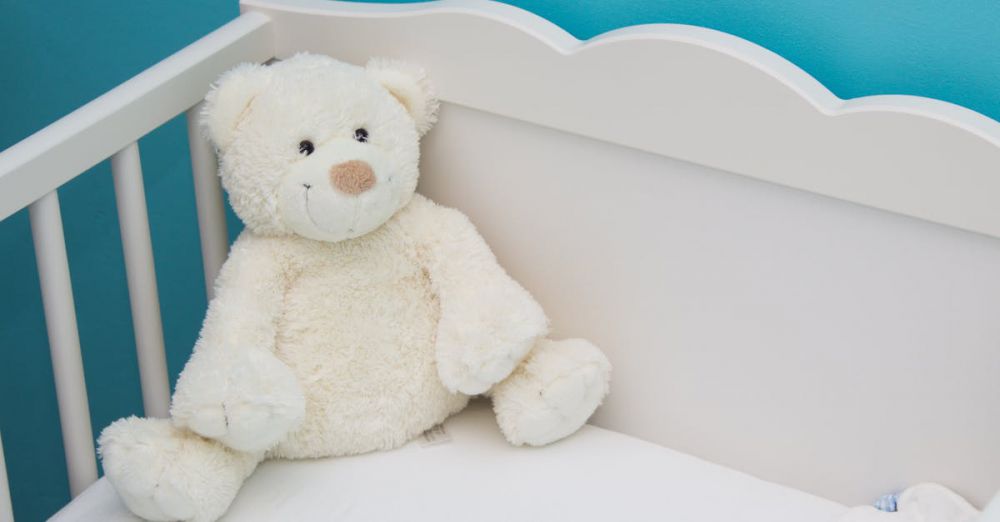 Crib - Soft teddy bear in a white crib against a vibrant blue wall, creating a comforting nursery atmosphere.