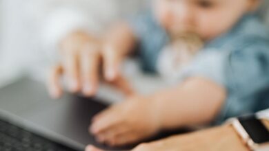 Baby Monitors - A mother and her baby engage with a laptop, showcasing multitasking in a modern workspace.