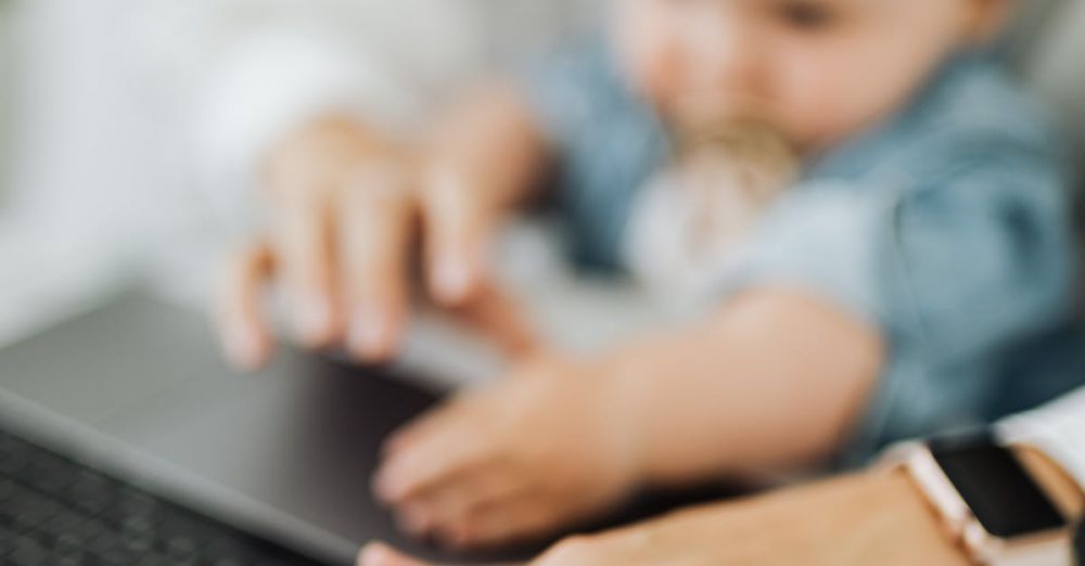 Baby Monitors - A mother and her baby engage with a laptop, showcasing multitasking in a modern workspace.