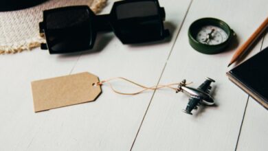 Travel Accessories - Flat lay of travel essentials including airplane model, sunglasses, compass, and hat on a table.