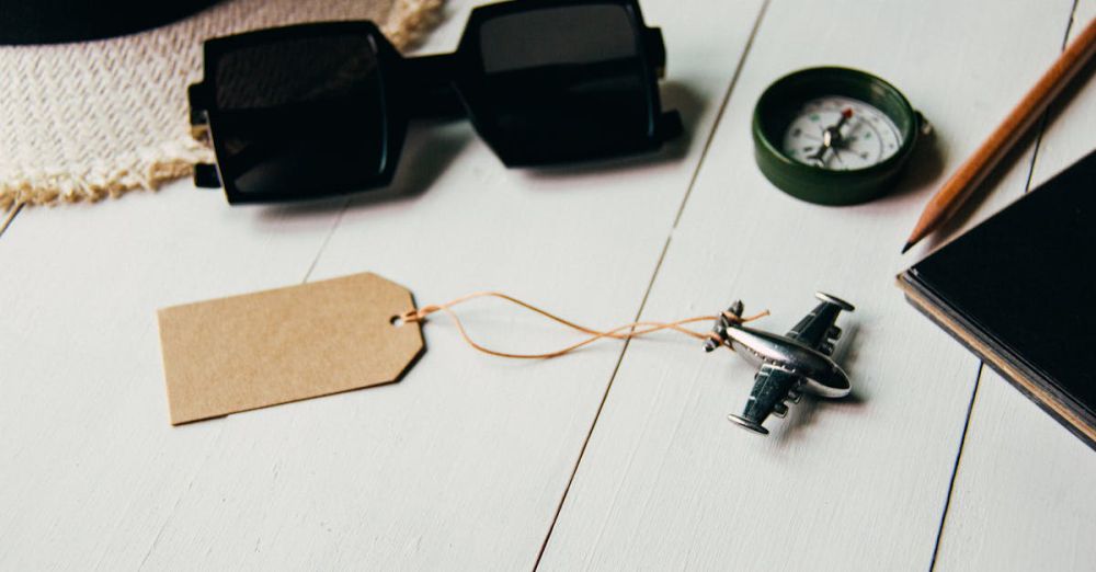 Travel Accessories - Flat lay of travel essentials including airplane model, sunglasses, compass, and hat on a table.