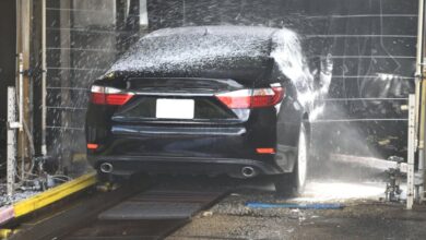 Car Wash - A black car being cleaned in an automated car wash with water and foam.