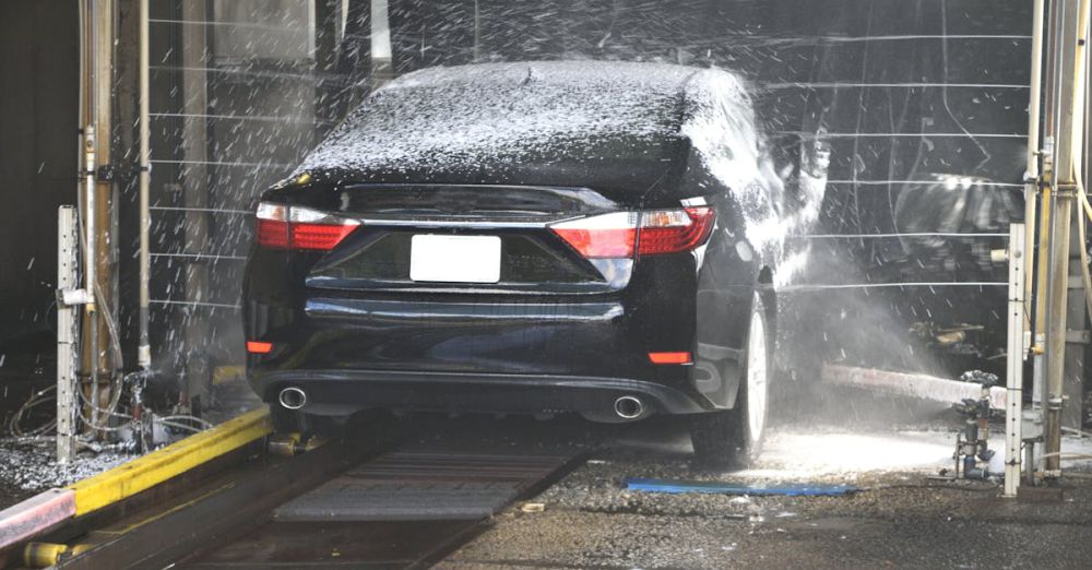 Car Wash - A black car being cleaned in an automated car wash with water and foam.