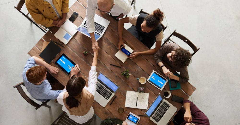 All-In-One Computers - Top view of a diverse team collaborating in an office setting with laptops and tablets, promoting cooperation.