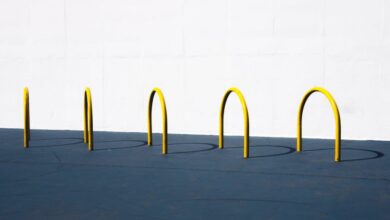 Bike Racks - A minimalist image featuring yellow bike racks casting shadows on a blue surface against a white wall.