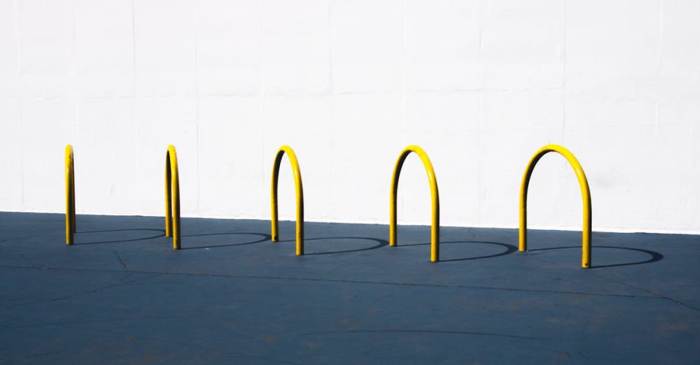 Bike Racks - A minimalist image featuring yellow bike racks casting shadows on a blue surface against a white wall.