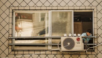 Air Compressors - Man looks outside a window with an LG air conditioner unit visible, creating a reflective effect.