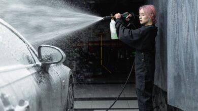 Wipers - Young woman cleaning a car with a high-pressure hose inside a garage, creating a splash of water and foam.
