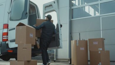 Cargo Boxes - A delivery man unloading cardboard boxes from a van at a warehouse during the day.