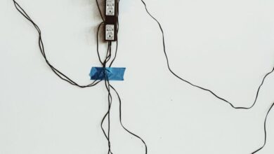 Power Strips - A display of tangled cables and multiple power sockets taped to a wall, showcasing chaotic technology setup.