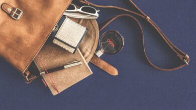 Leather Goods - Stylish flat lay of a leather handbag with luxury accessories including sunglasses, wallet, notebook, and pen.