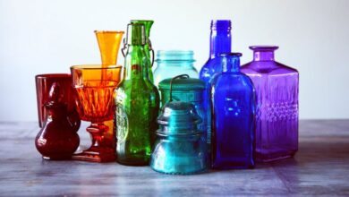 Glassware - A captivating array of multicolored vintage glass bottles and containers on a wooden table.