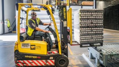 Packaging - A warehouse worker maneuvers a forklift to transport crates for brewing company storage.