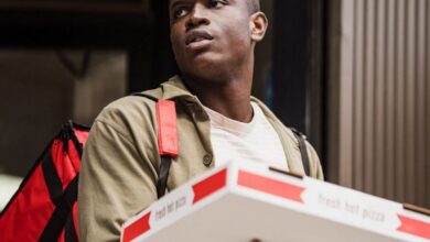 Food Bags - A delivery person holds pizza boxes outdoors with a red backpack, ready for delivery.