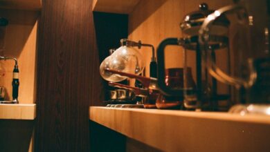 Coffee Makers - Warm indoors scene of a wooden shelf with various coffee makers and accessories.