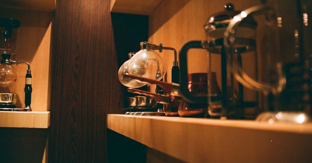 Coffee Makers - Warm indoors scene of a wooden shelf with various coffee makers and accessories.