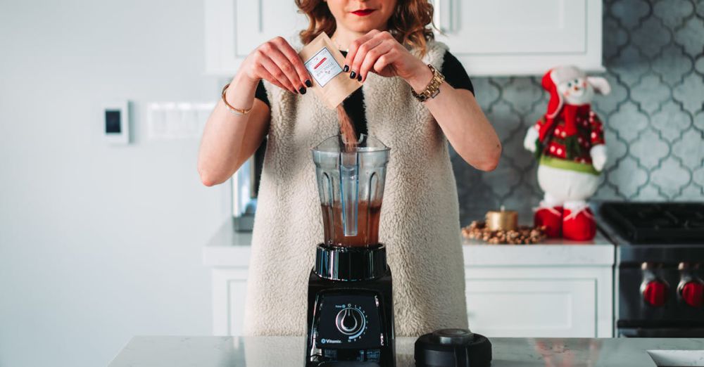 Blender - A woman pours a sachet into a blender in a festive kitchen setting.