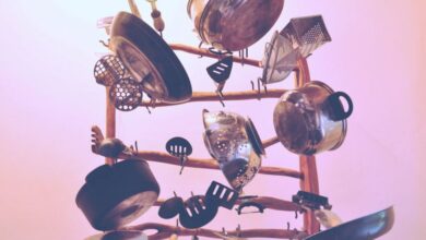 Cookware - Artistic assortment of hanging kitchen cookware and utensils on a wooden rack indoors.