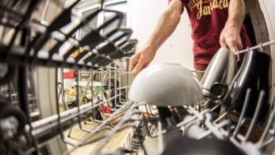 Dishwasher - POV perspective of an adult loading dishes into a dishwasher in a home kitchen.