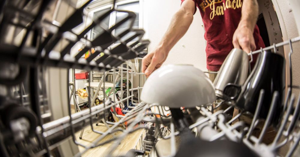 Dishwasher - POV perspective of an adult loading dishes into a dishwasher in a home kitchen.