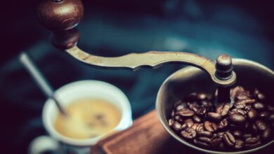 Coffee Grinder - Close-up of a vintage coffee grinder with fresh coffee beans next to a steaming cup.