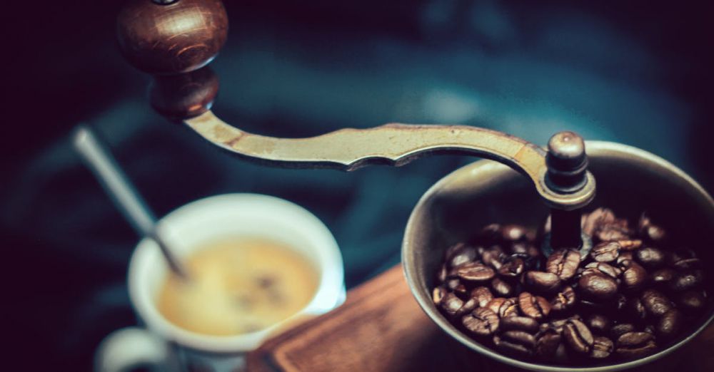 Coffee Grinder - Close-up of a vintage coffee grinder with fresh coffee beans next to a steaming cup.