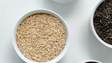 Rice Cooker - A variety of rice and grains displayed in white ceramic bowls on a clean white surface.