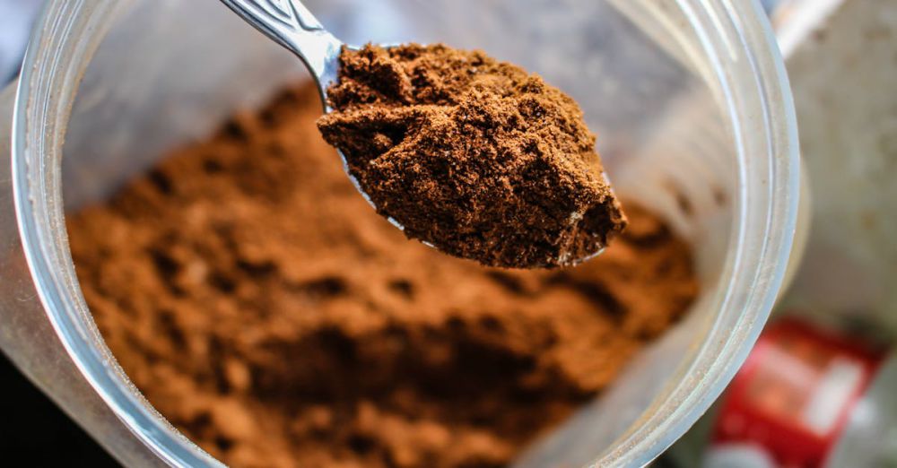 Protein Powder - Focused shot of a spoon scooping cocoa powder from a container, emphasizing texture.