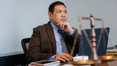 Smart Scales - Asian lawyer at work with laptop and legal scales, focused and thoughtful.