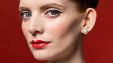 Pearl Necklaces - Beautiful woman in 1950s fashion with pearl necklace and victory rolls against red backdrop.