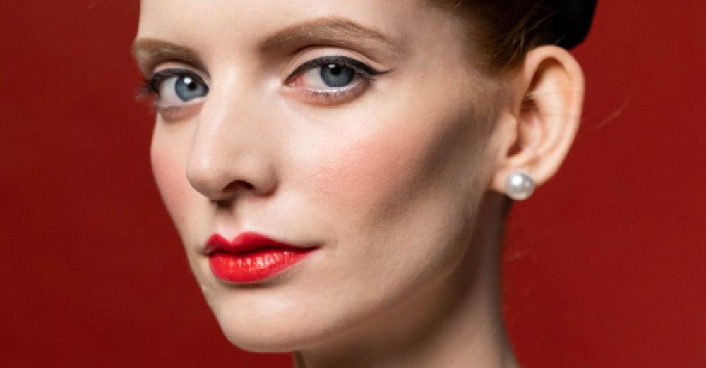 Pearl Necklaces - Beautiful woman in 1950s fashion with pearl necklace and victory rolls against red backdrop.