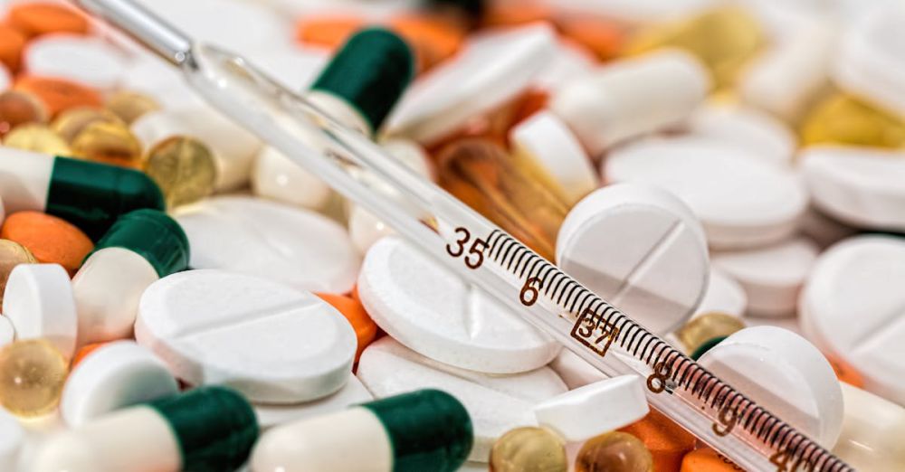 Thermometers - Close-up image showing various pills and a thermometer, emphasizing health and medicine.