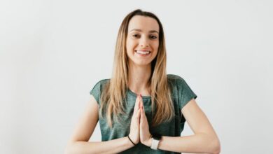 Wearable Cameras - Cheerful woman in green shirt practicing yoga indoors, embracing peace and wellness.