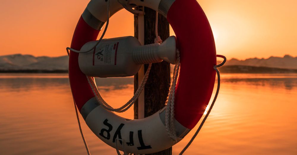 Safety Devices - A lifebuoy hanging on a wooden post at sunset, with a calm sea and warm hues creating a serene nautical scene.