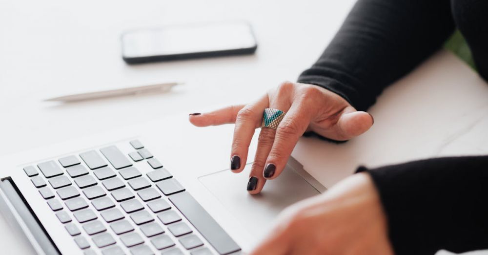 Smart Jewelry - A businesswoman's hands typing on a laptop at a bright, modern workspace.