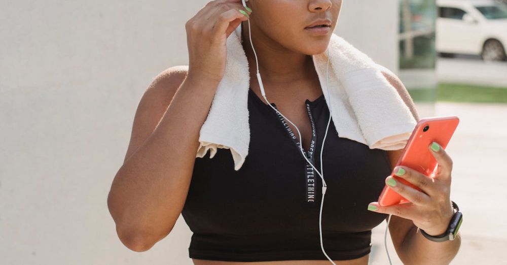 Running Gadgets - A young woman in activewear with earphones and phone, ready for an outdoor workout.