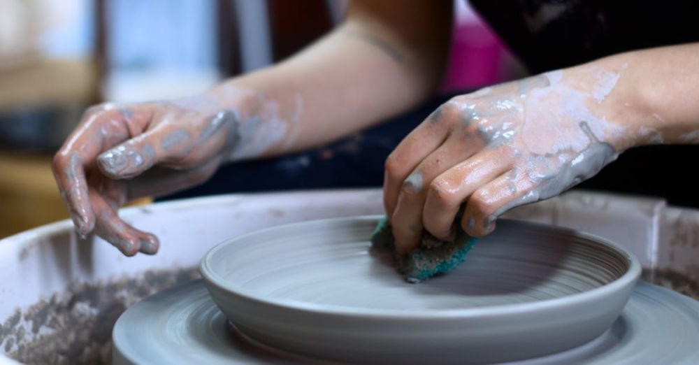 Pottery - Close-up of hands shaping pottery clay on a spinning wheel in a creative studio.