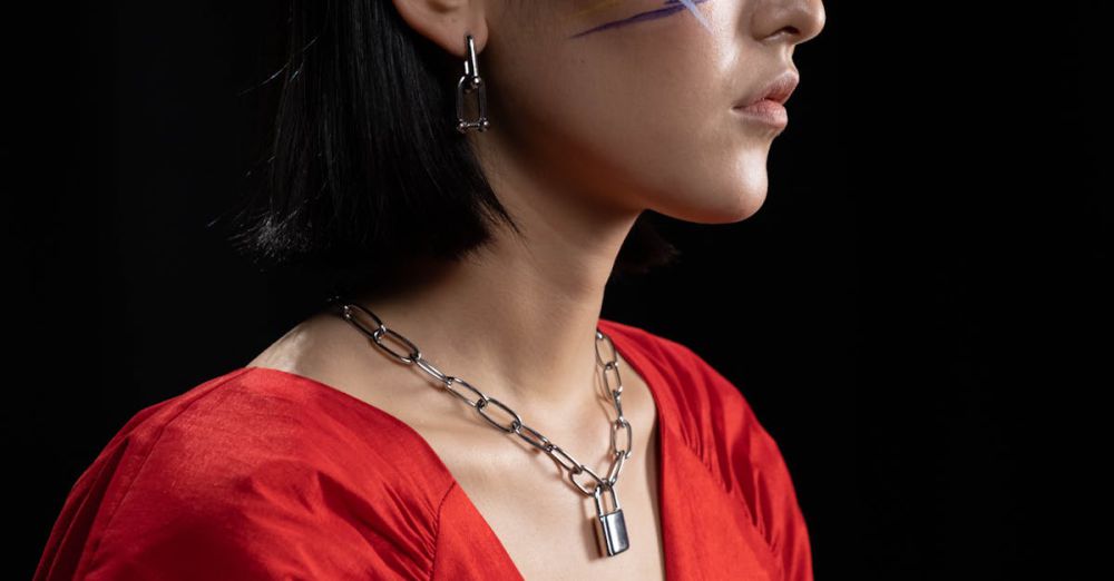 Jewelry - Artistic side profile portrait of a woman with face paint and bold jewelry on a black background.