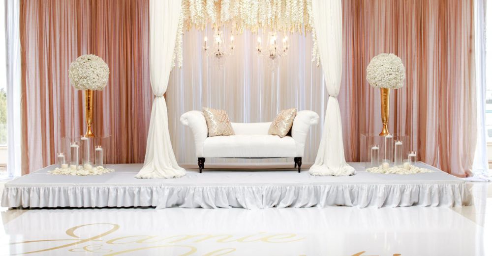 Decorations - A beautifully styled wedding stage featuring white furniture and floral decorations.